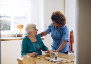 Photo of caregiver serving food to older woman.